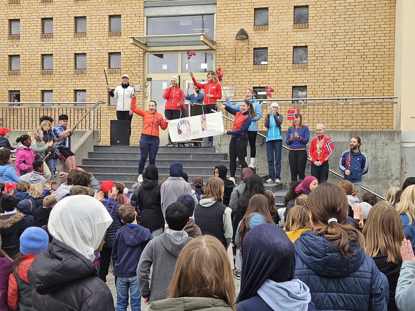 en gruppe mennesker som står på en scene med et skilt foran en folkemengde