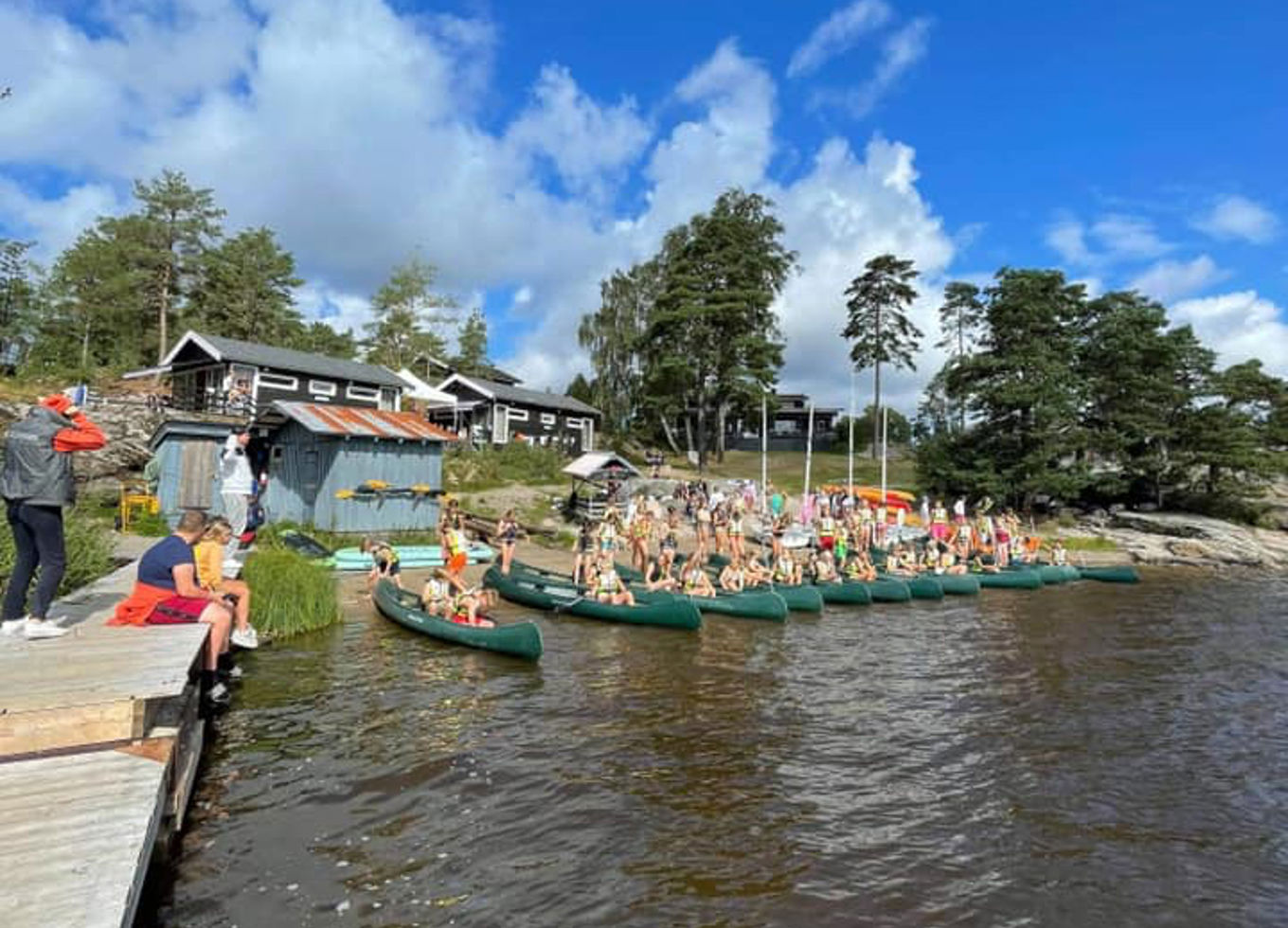 En gruppe mennesker på en brygge ved siden av et vann En gruppe mennesker på en brygge ved siden av et vann